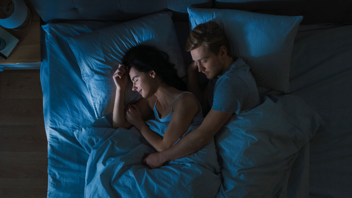 couple sleeping together, with one's arm around the other