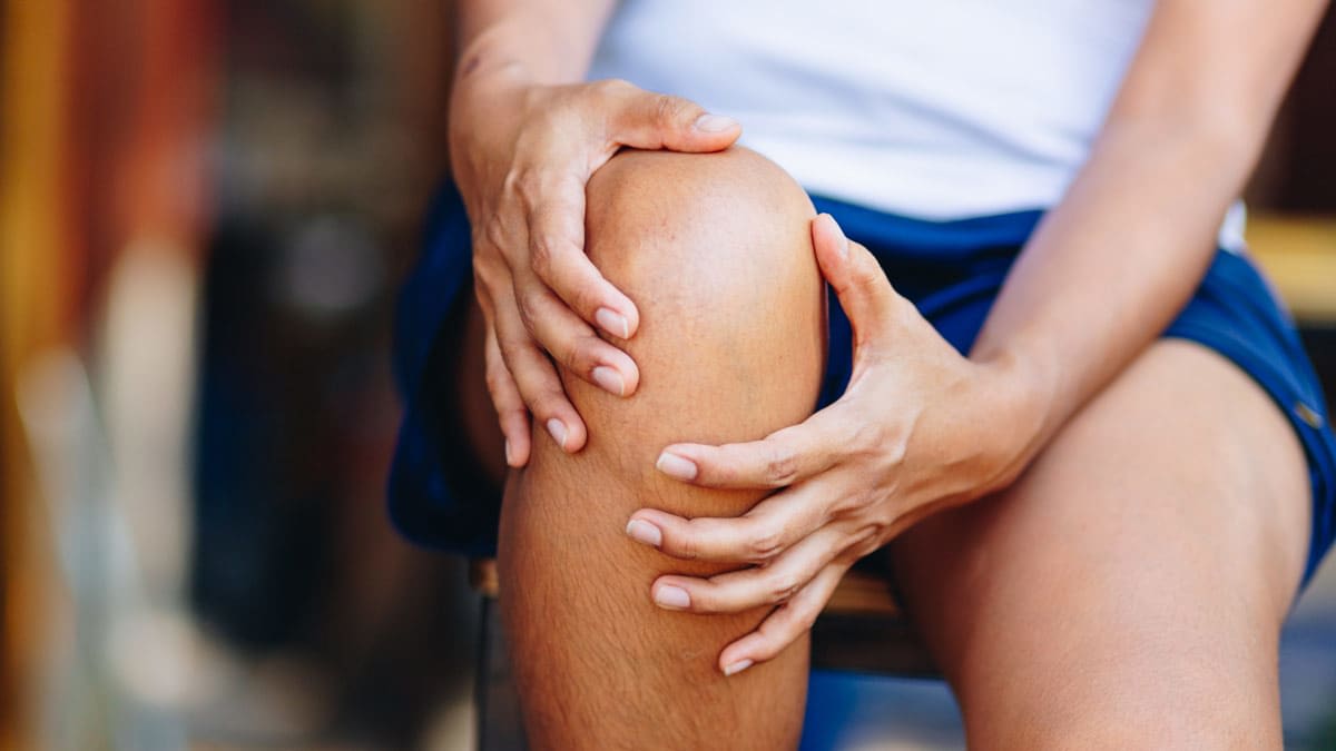close up of person's hands on knee as though they're in pain