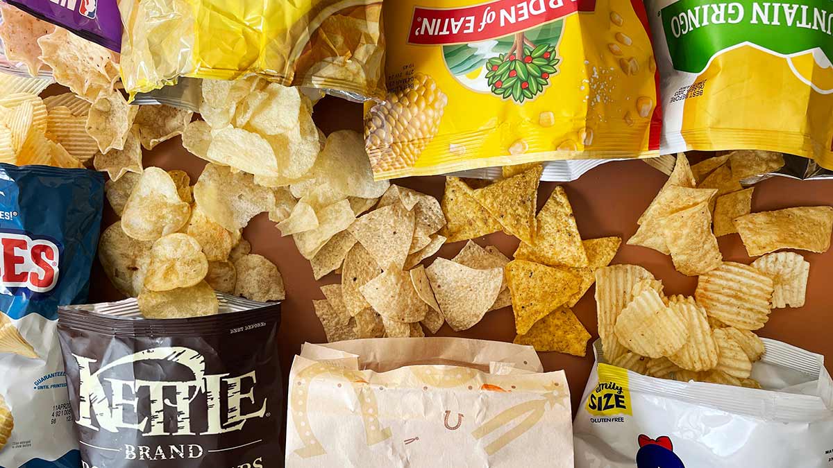 tortilla chips and potato chips spilling out of chip bags