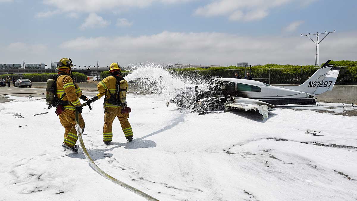 Firefighters put foam on the remains of a small plane that crashed on the 405 freeway in Irvine, California, on Friday, June 30, 2017.