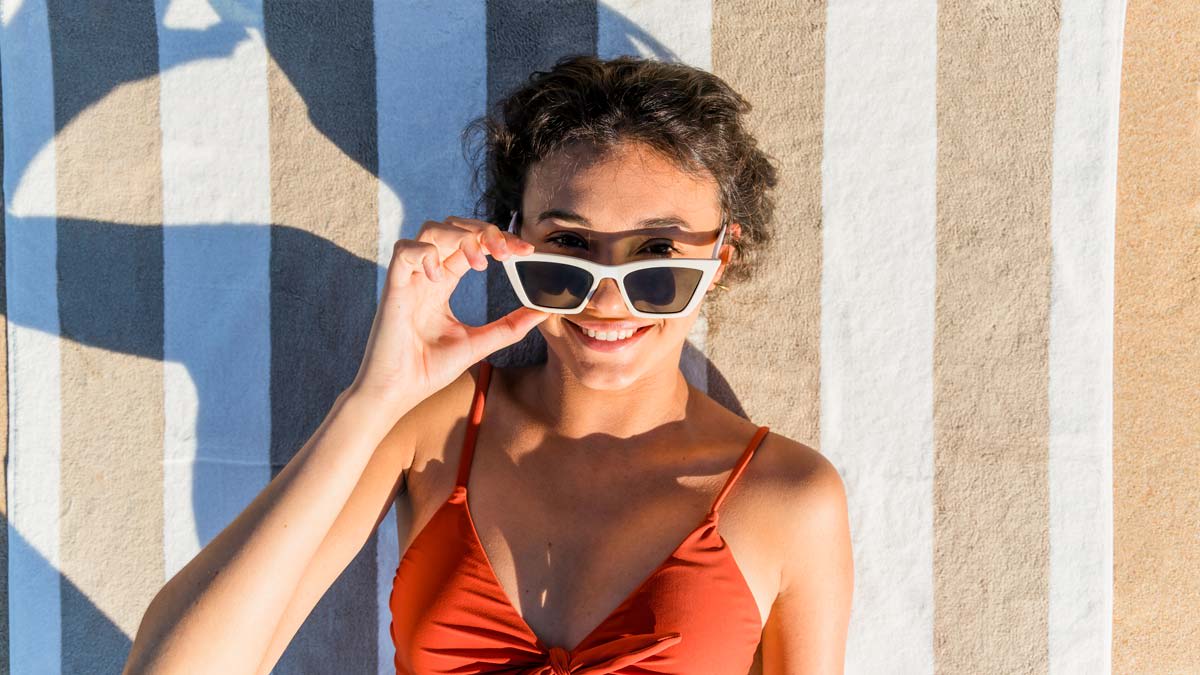 girl laying on a beach towel wearing sunglasses