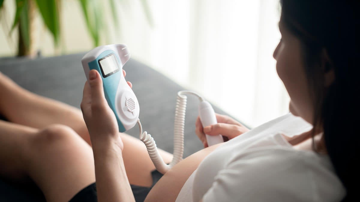 A person using a portable fetal doppler during pregnancy.