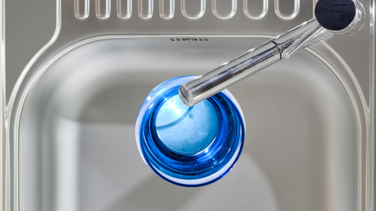 A glass of water being poured from a sink faucet.