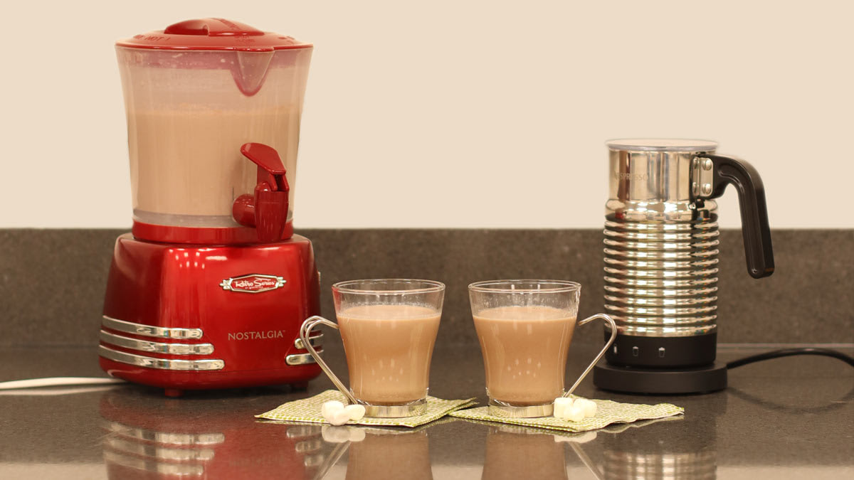 a Nostalgia Retro Frother and Hot Chocolate Maker and Dispenser and a Nespresso Aeroccino 4 Milk Frother with two cups of hot chocolate