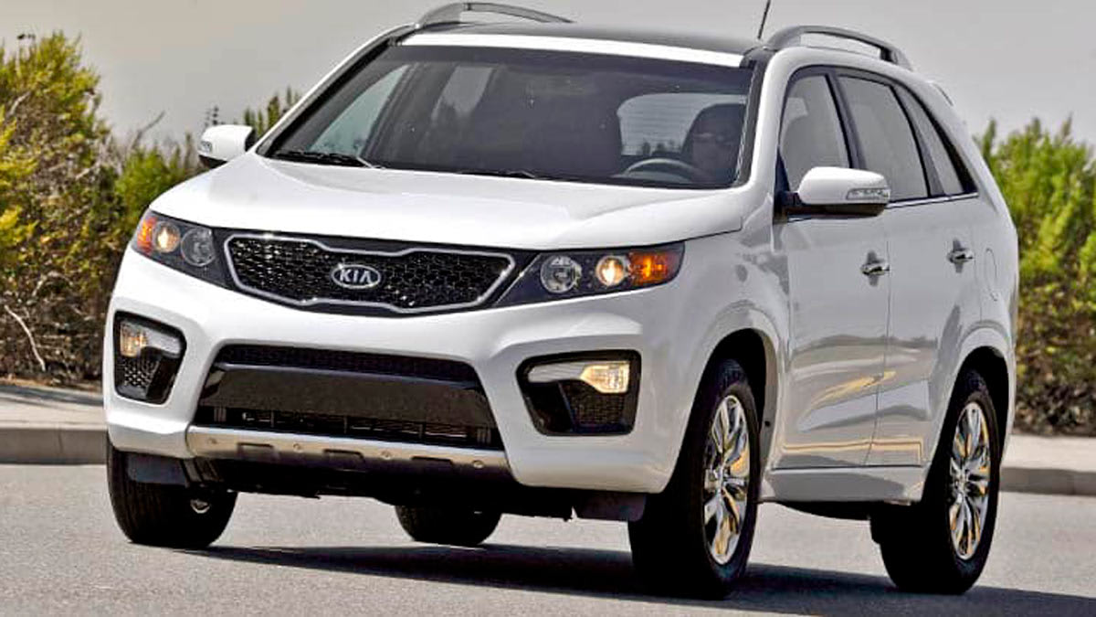 white 2012 Kia Sorento on road with sidewalk and bushes in background