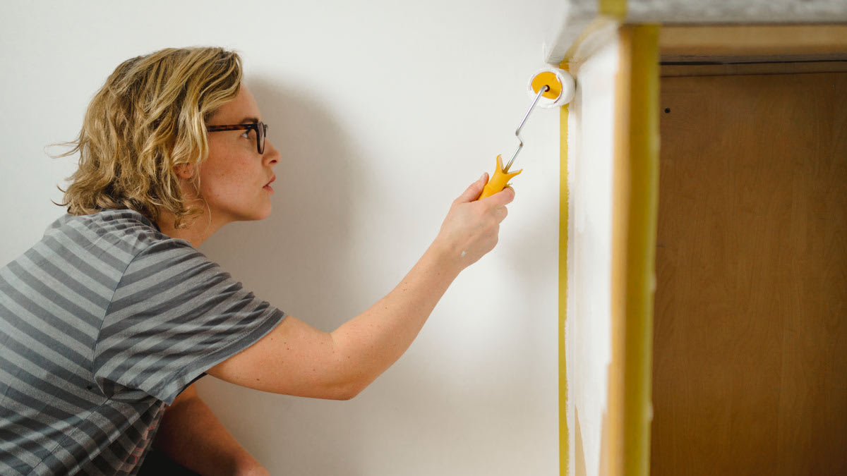 A woman painting kitchen cabinets