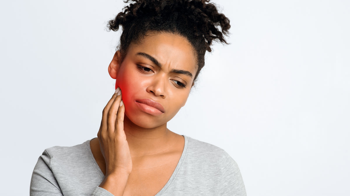 person with hand on jaw as though they're in pain, illustrated red glow around pain spot