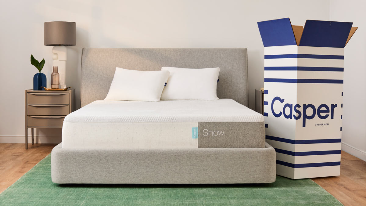Casper Snow mattress on bed frame and open Casper box next to the bed