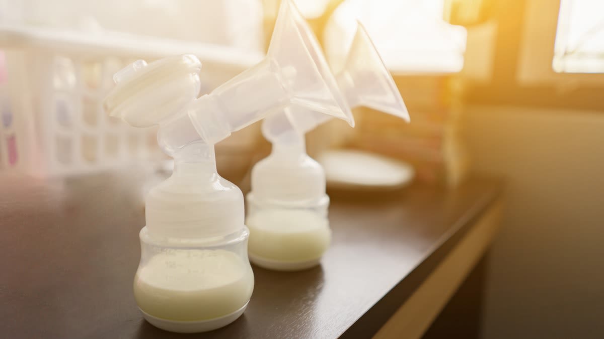 Two bottles filled with breast milk with breast pump flanges attached