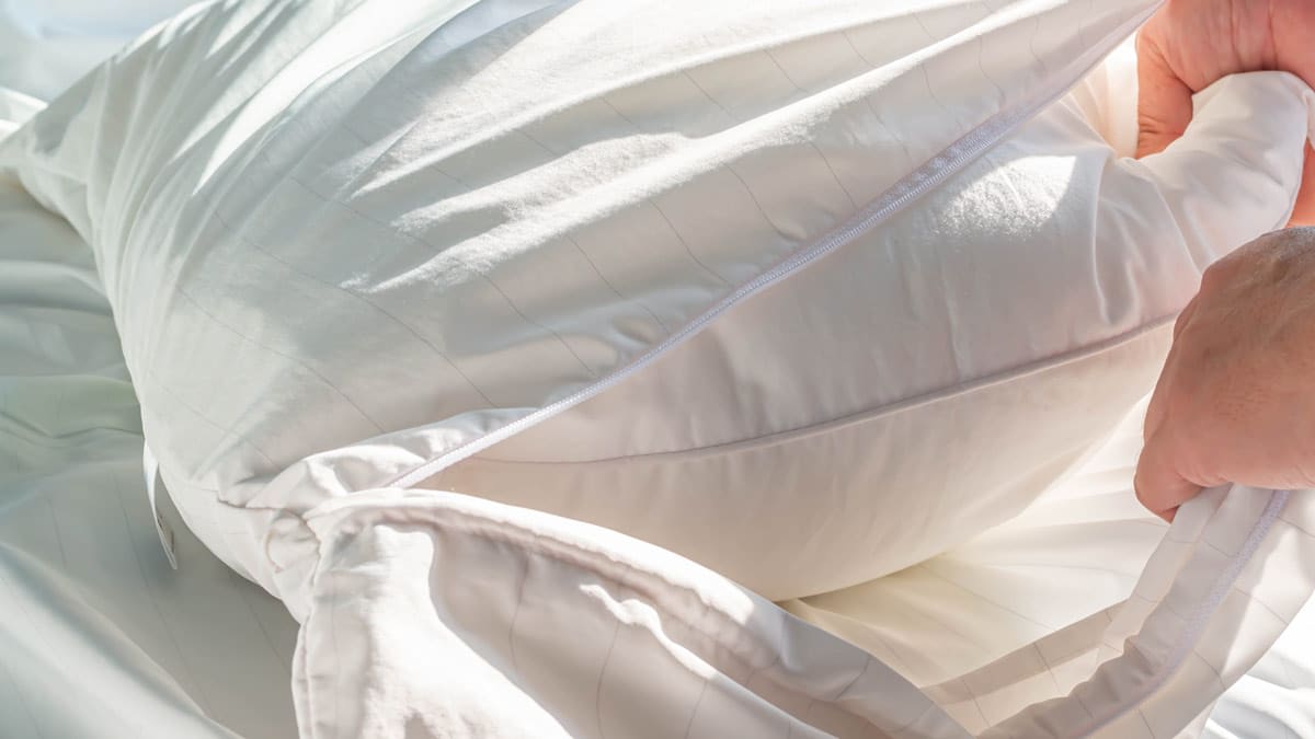 close up of hands putting pillow into pillow protector