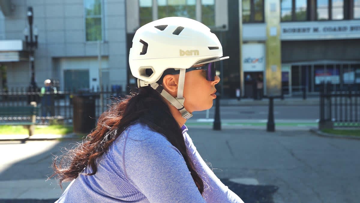 A woman wearing a Bern Hudson Bike Helmet while riding a bike