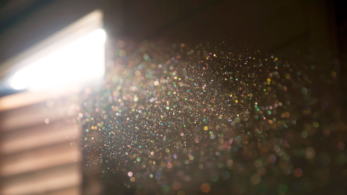 sunbeam highlighting dust particles in home with blurred window and blinds in background