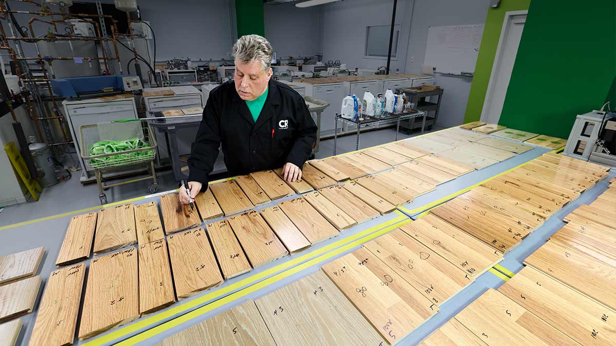 A Consumer Reports technician inspecting wood floor samples after testing with hardwood floor cleaners.