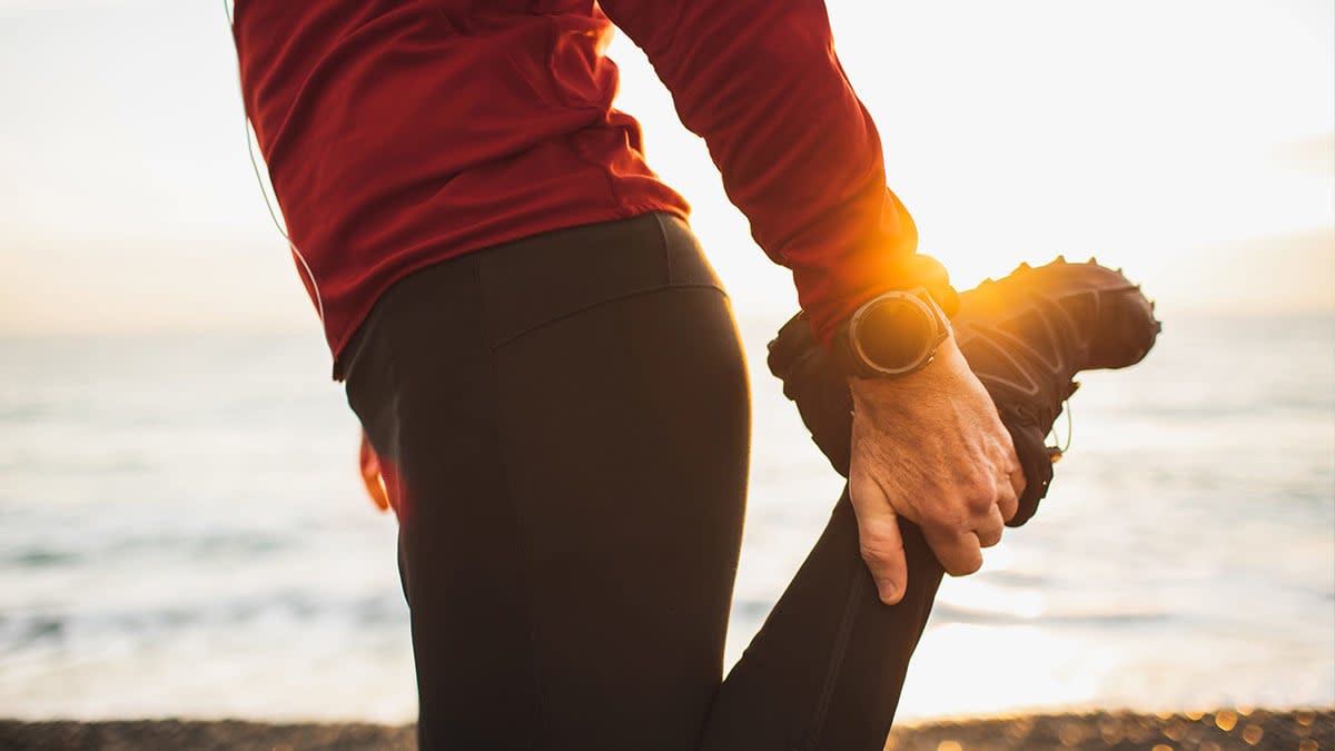Person stretching by holding their ankle behind them while standing on one foot.