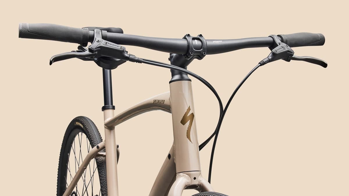top half of Specialized Sirrus X 3.0 road bike on beige background