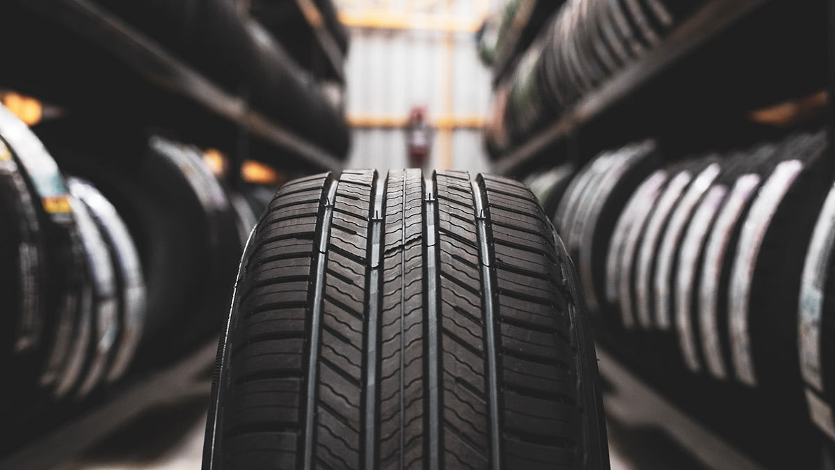 A tire up close in the middle of an aisle full of tires on both sides.