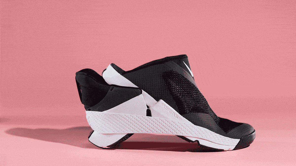 A foot wearing a white athletic sock slipping into the Nike Go FlyEase sneaker.