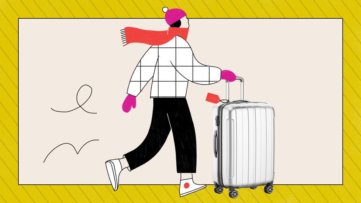 A person in winter clothes walking with a silver suitcase.