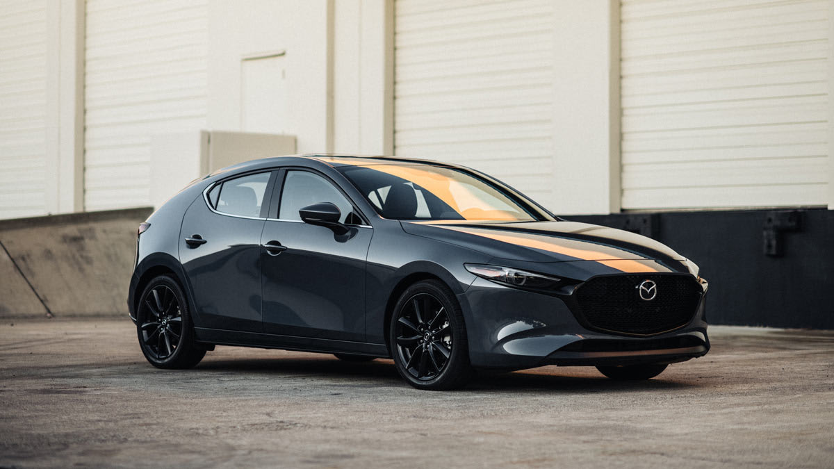 2026 Mazda3 in grey on concrete with white industrial building in background