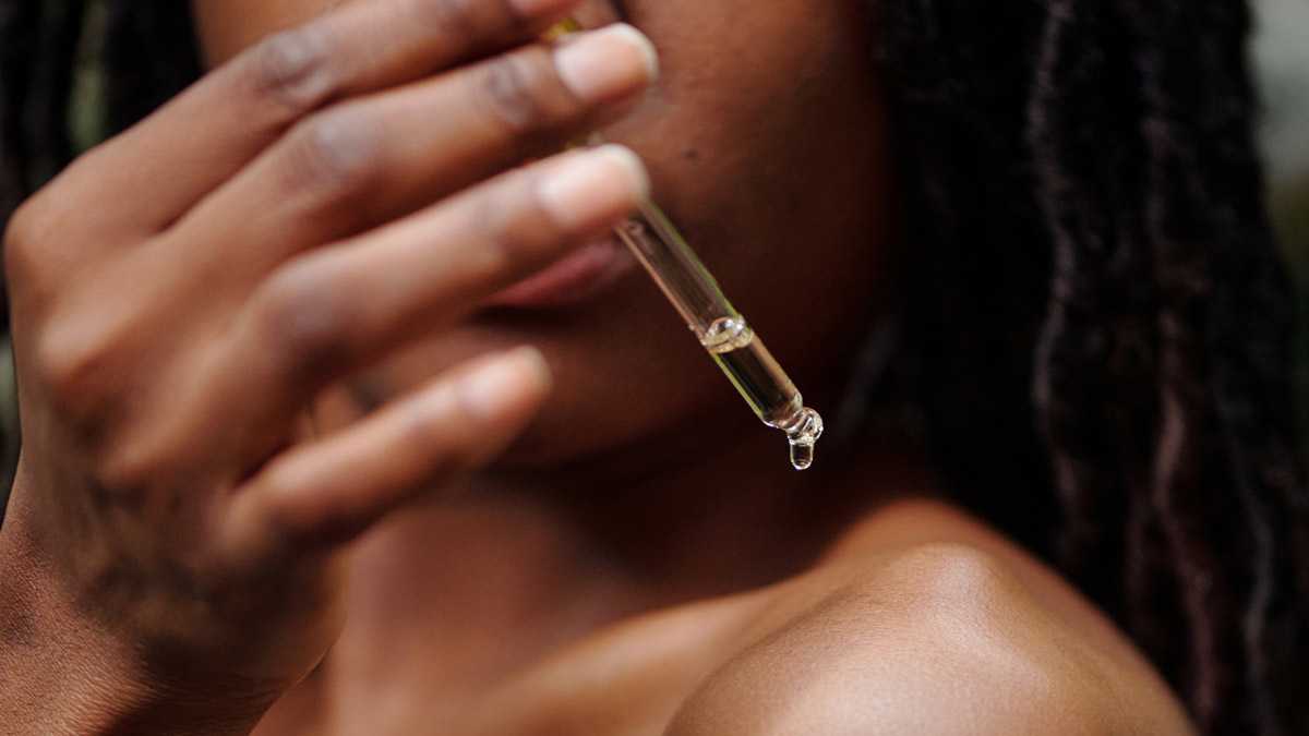 Woman applying body oil from a dropper