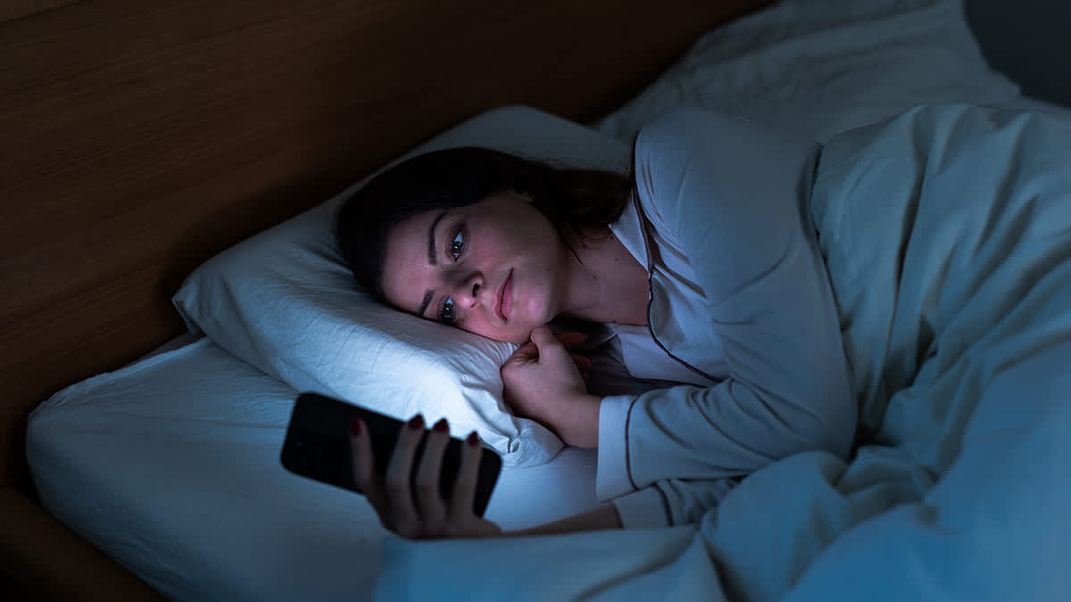 Woman in bed looking at phone (Can't Sleep)