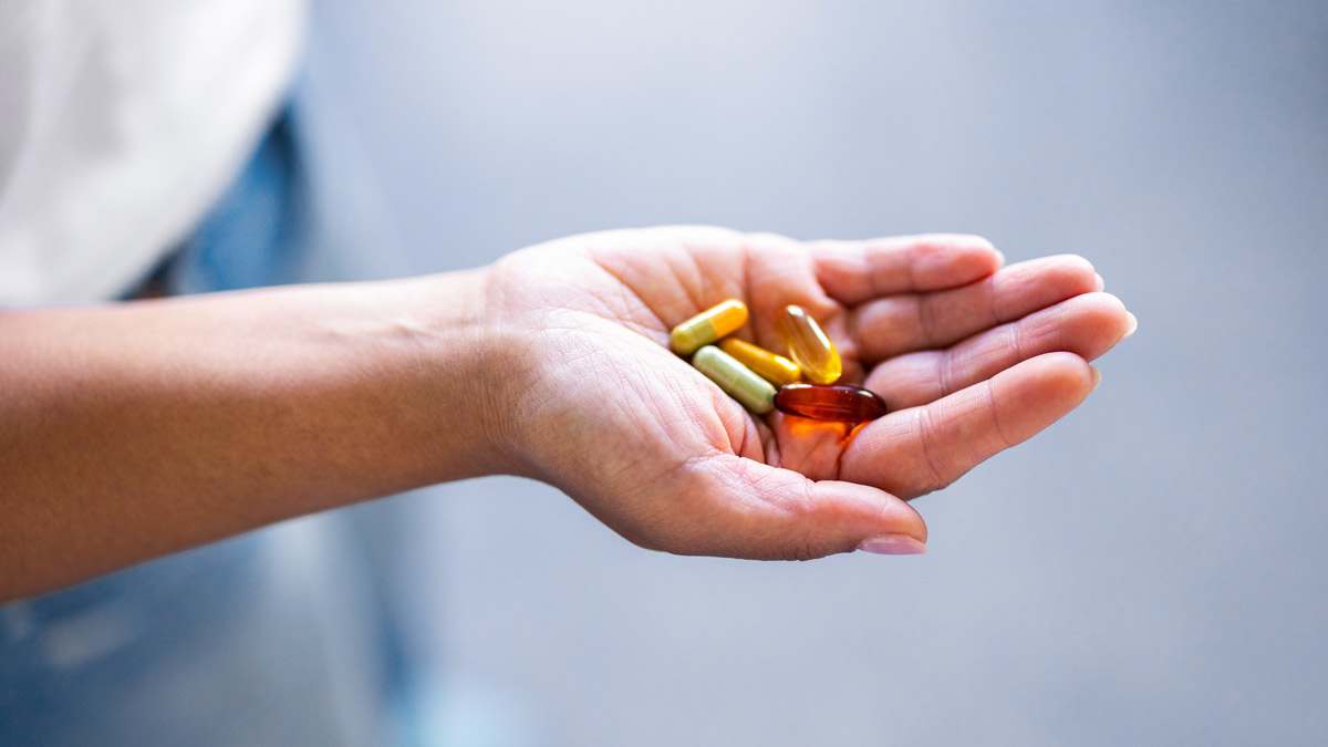 hand holding various supplements with grey background