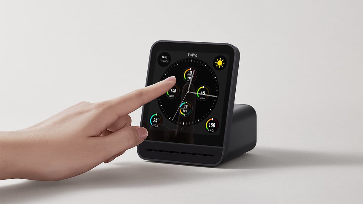 A handing reaching out to touch the face of the QingPing Air Monitor 2