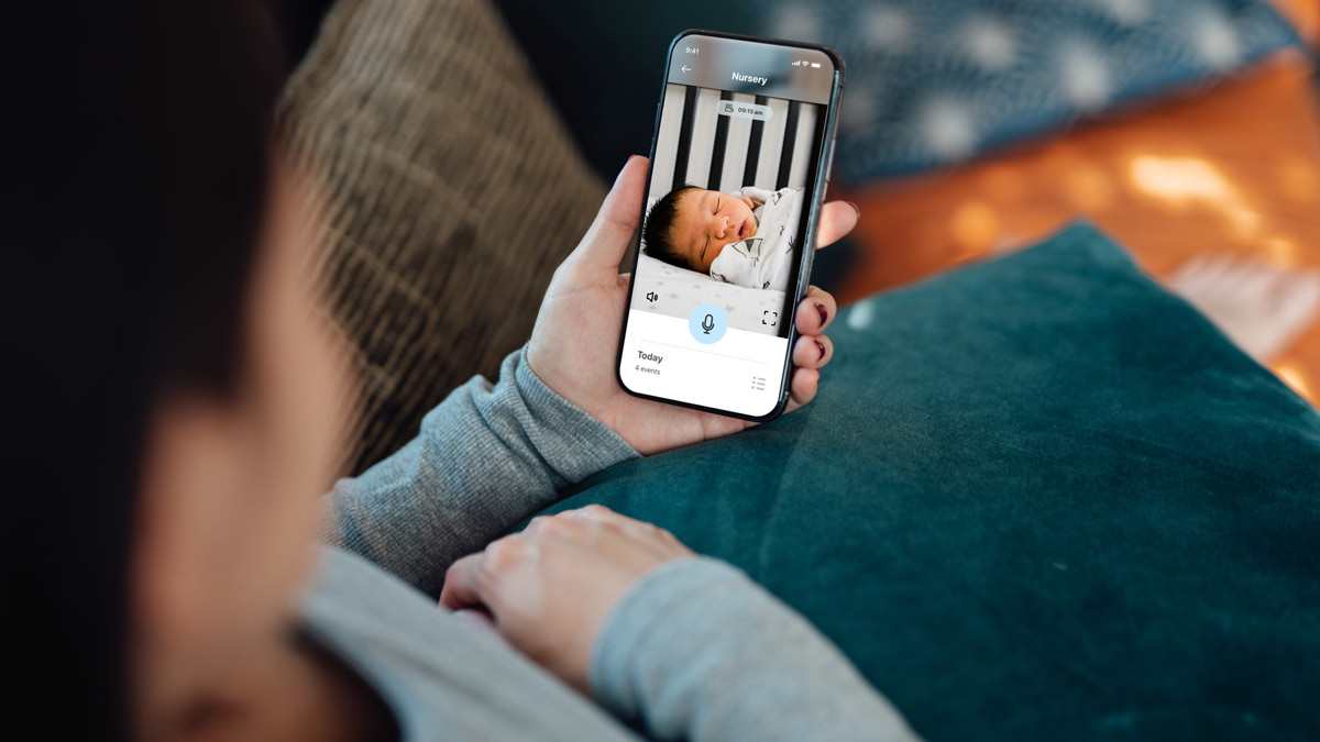 Parent looking at baby sleeping on phone through baby monitor