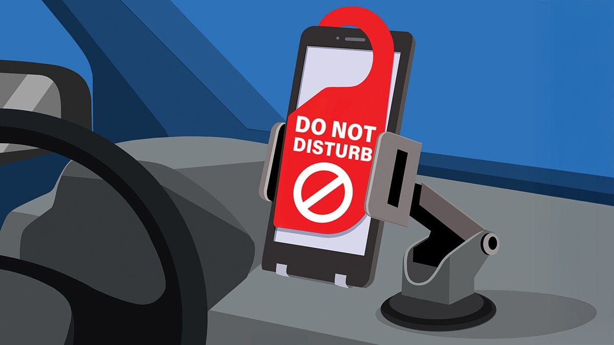 An illustration of a smartphone in a car mount with a red "Do Not Disturb" sign.