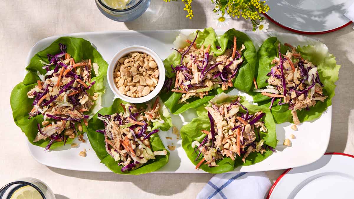 A white platter with five lettuce wraps filled with Crunchy Peanut Chicken Salad