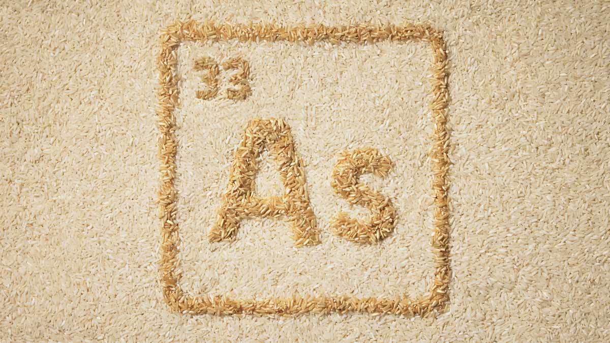 Periodic table-style symbol for arsenic  formed from brown rice grains against a background of uncooked white rice