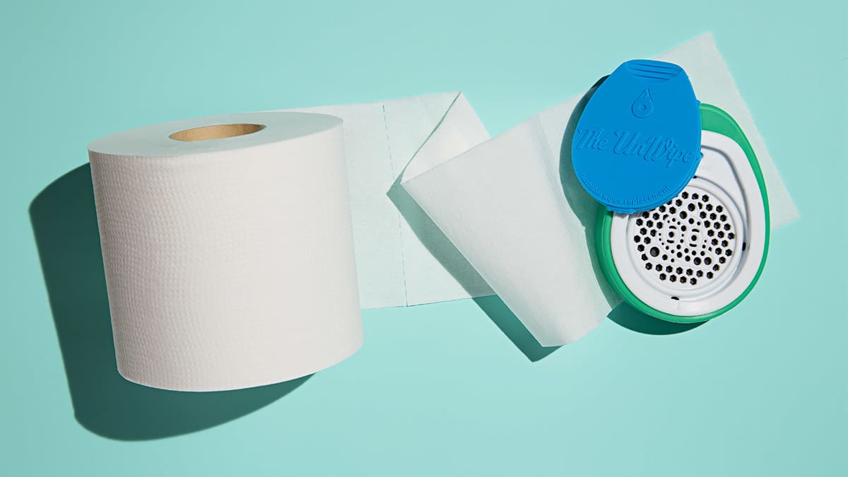 A roll of toilet paper unrolled with the UnWipe sitting on top of the paper.