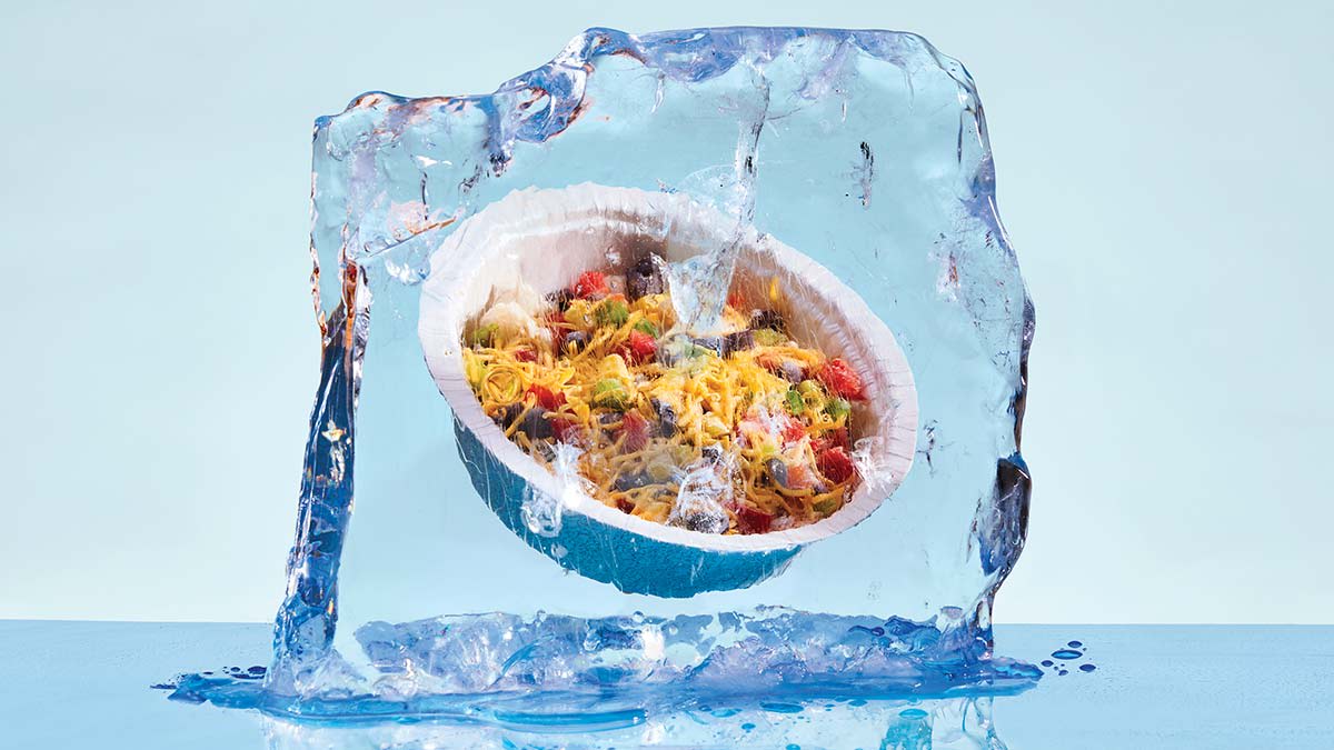 A meal frozen solid inside a large, melting block of clear ice.