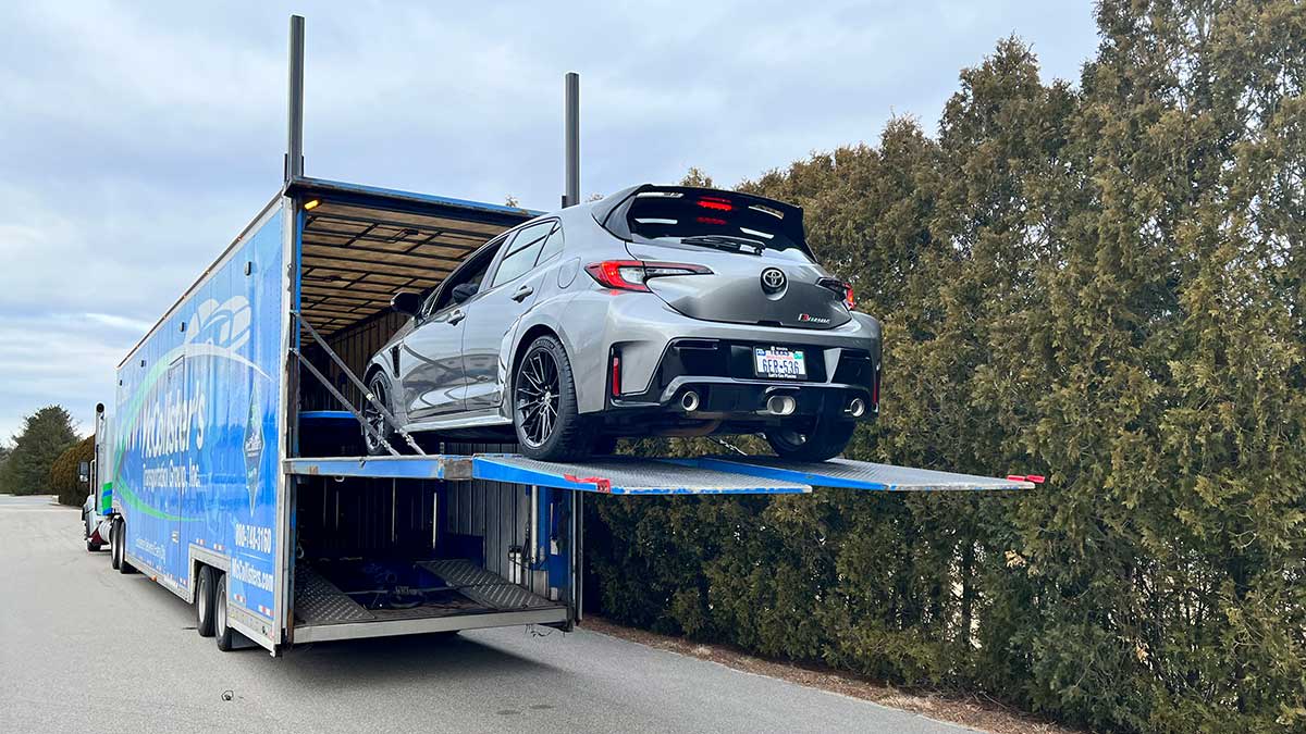 A car being lifted into a vehicle transportation truck.