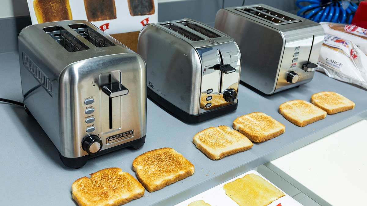 Testing shot of three toasters with toasted slices of bread in from of them.