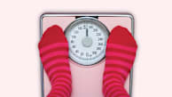 overhead view of feet with pink and red striped socks on scale that says "uh oh!", pink background