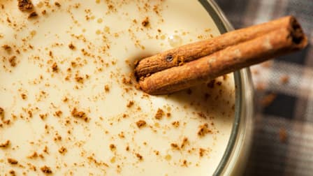 eggnog in glass with cinnamon stick garnish