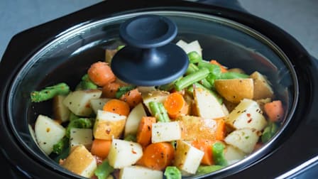 Slow cooker with vegetables cooking inside.