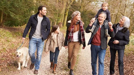 multi-generational family with dog walking on trail in cold weather