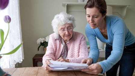 person looking over documents with elderly person