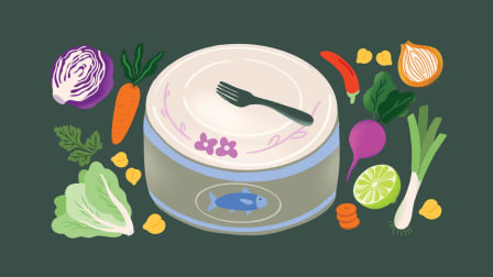 Can of tuna with plate on top and fork surrounded by fresh ingredients