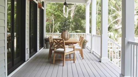 Table and chairs sit out on composite harvest decking on a front porch.