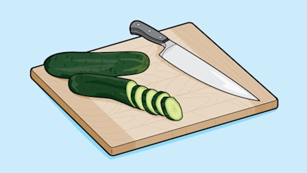 Chef knife on cutting board with sliced cucumber