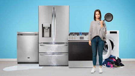 person holding frying pan in front of broken range with broken dishwasher, refrigerator, and washing machine next to it