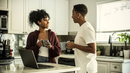 A Black couple speaking in their kitchen.