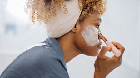 woman applying white cream to her face