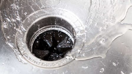 water going down a garbage disposal in a sink