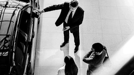 A dealership salesperson showing a car to a couple.