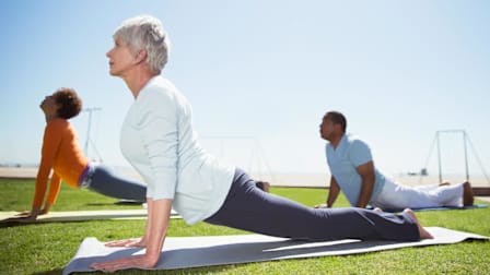 Seniors practicing yoga in sunny beach park