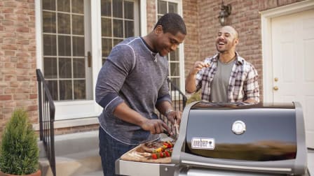 Two men outside talking while grilling on the Weber Spirit E-210 Gas Grill